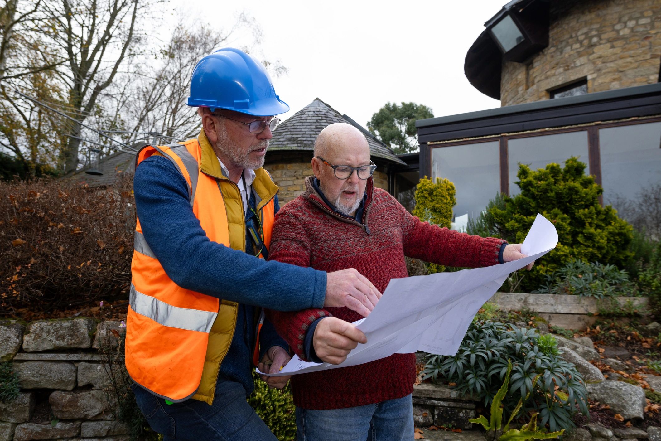 Contractor reviewing plans with a client outside a home
