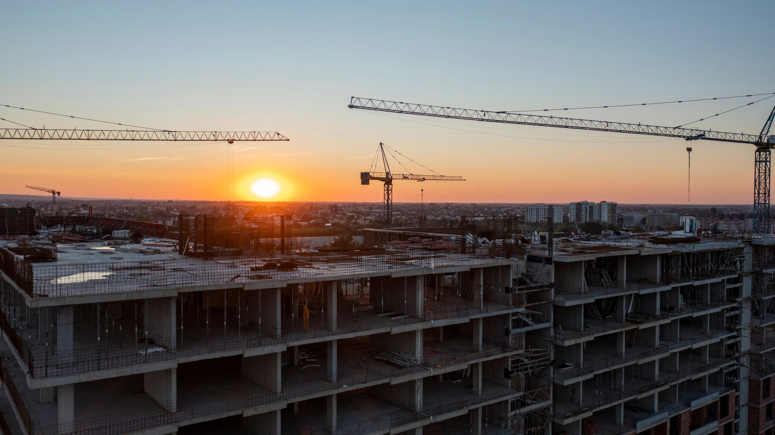 Large concrete building construction site at sunset