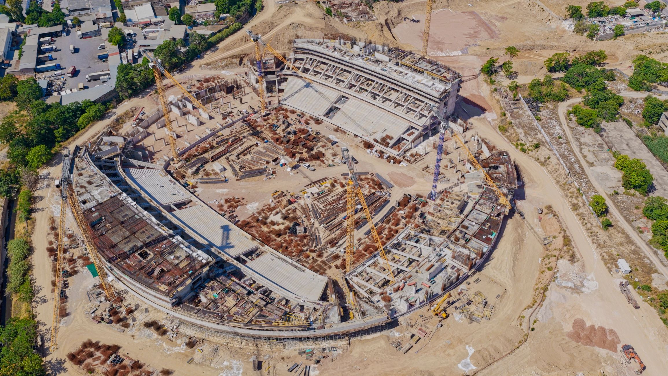 Aerial view of large stadium construction site with cranes